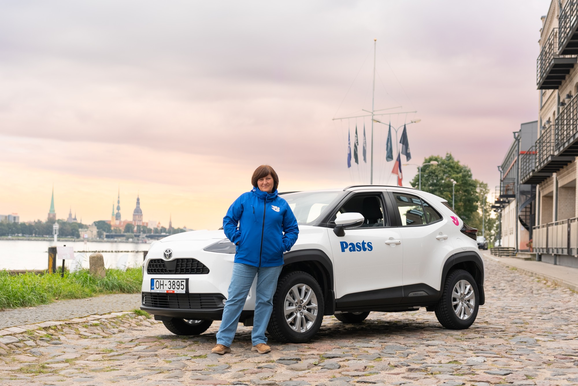 241020-53 Pastniece stāv pie auto